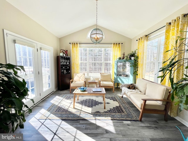 sitting room featuring a healthy amount of sunlight, vaulted ceiling, dark wood-type flooring, and a notable chandelier