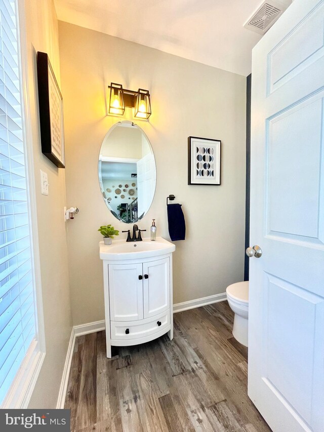 bathroom with hardwood / wood-style flooring, vanity, and toilet