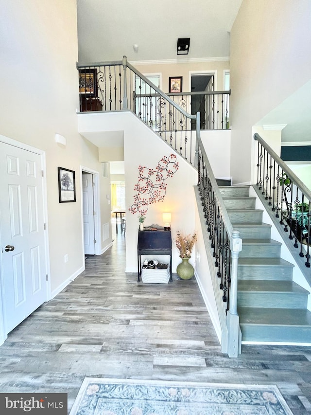 stairs featuring hardwood / wood-style floors, a towering ceiling, and ornamental molding