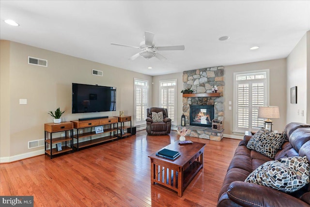 living room with ceiling fan, wood-type flooring, a healthy amount of sunlight, and a fireplace