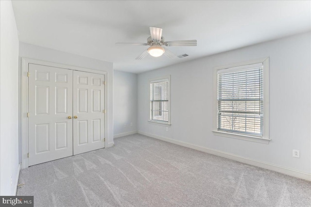 unfurnished bedroom with ceiling fan, a closet, and light colored carpet