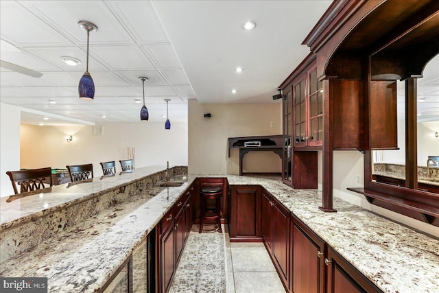 bar featuring light tile patterned floors, sink, light stone counters, and pendant lighting