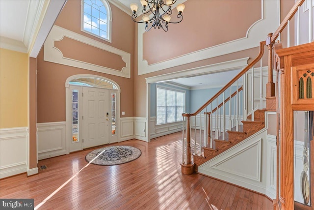 foyer with hardwood / wood-style floors, crown molding, and a notable chandelier