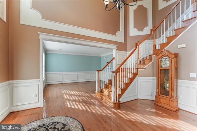 entryway with hardwood / wood-style floors, ornamental molding, and a chandelier