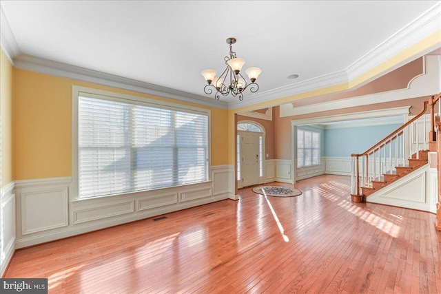 foyer with crown molding, plenty of natural light, and a notable chandelier