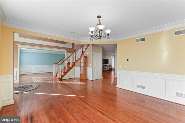 empty room featuring hardwood / wood-style flooring, ornamental molding, and an inviting chandelier