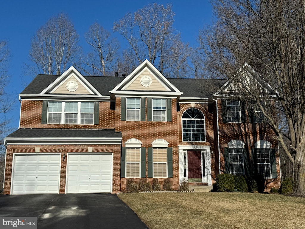 view of front of home with driveway, a garage, roof with shingles, a front lawn, and brick siding