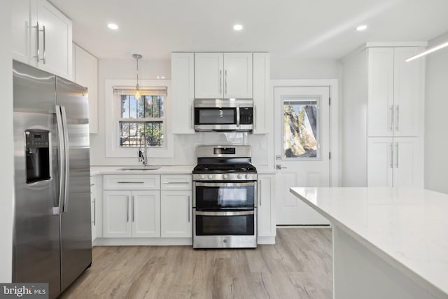 kitchen featuring appliances with stainless steel finishes, sink, hanging light fixtures, and white cabinets