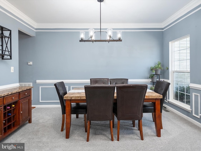 dining area with a notable chandelier, ornamental molding, and light colored carpet