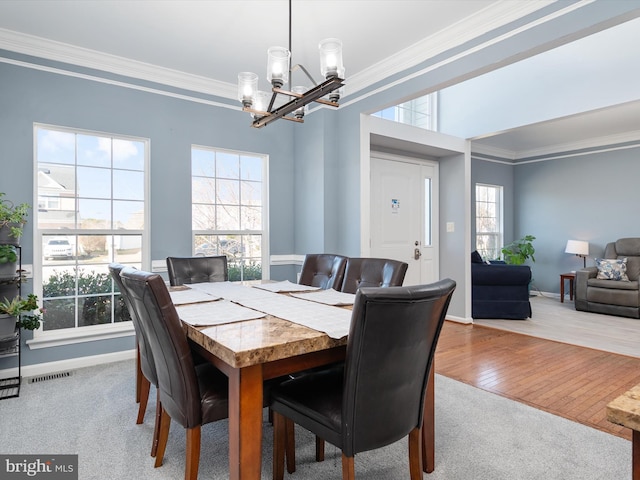 dining area with a notable chandelier, ornamental molding, and light hardwood / wood-style floors