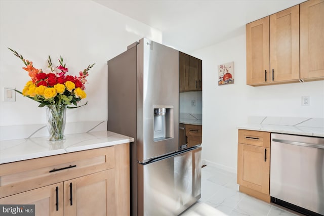 kitchen featuring light brown cabinetry, light stone counters, and appliances with stainless steel finishes