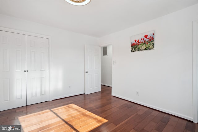 unfurnished bedroom with dark wood-type flooring and a closet