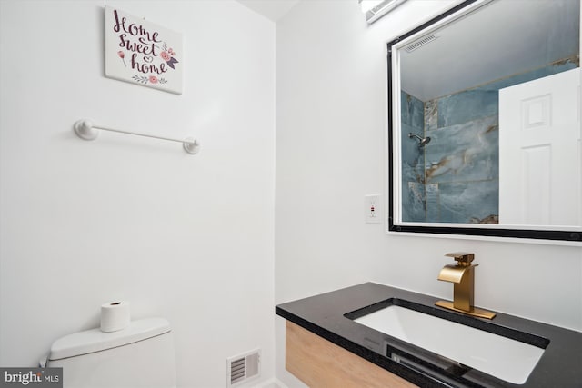 bathroom featuring toilet, vanity, and tiled shower