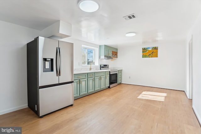 kitchen featuring sink, green cabinets, stainless steel appliances, and light hardwood / wood-style flooring