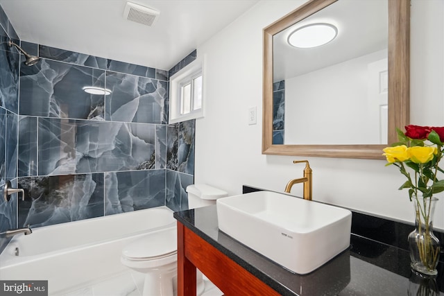 full bathroom featuring toilet, tiled shower / bath, and vanity