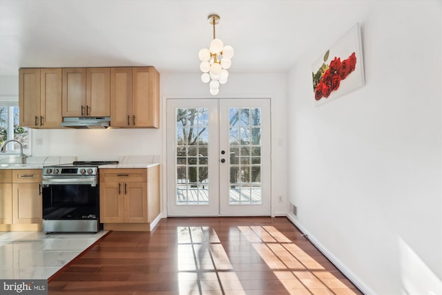 kitchen with stainless steel range, dark wood-type flooring, light brown cabinetry, french doors, and hanging light fixtures