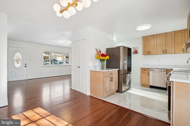 kitchen featuring stainless steel appliances, pendant lighting, a chandelier, and light hardwood / wood-style flooring