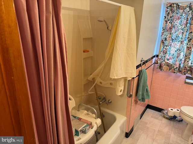 bathroom with toilet, shower / tub combo, and tile walls