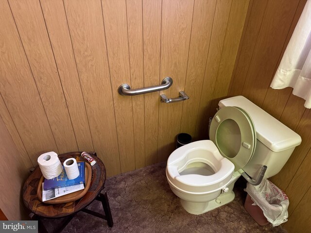 bathroom with toilet and wooden walls