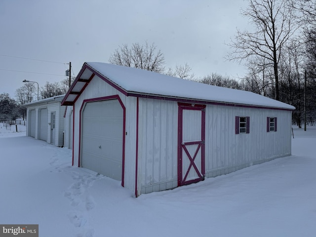 snow covered structure featuring a garage