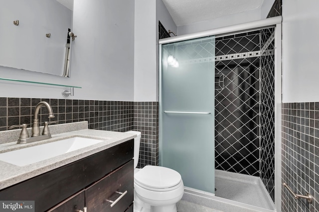 bathroom with a textured ceiling, an enclosed shower, vanity, tile walls, and toilet