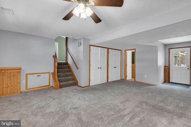 unfurnished living room featuring ceiling fan, light colored carpet, and a textured ceiling