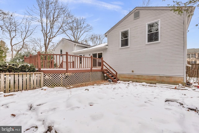 snow covered rear of property with a deck