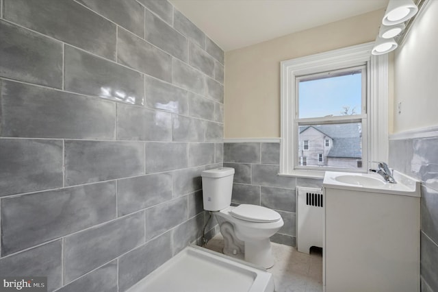 bathroom with toilet, tile walls, tile patterned floors, radiator, and vanity