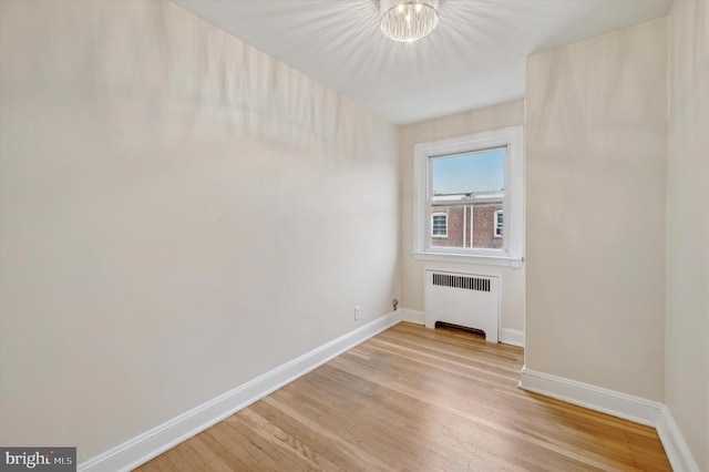 spare room with radiator heating unit and light hardwood / wood-style floors