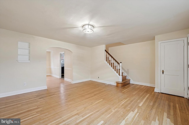 unfurnished living room featuring built in shelves and light hardwood / wood-style floors