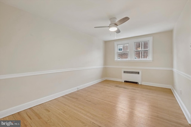 spare room with ceiling fan, light hardwood / wood-style floors, and radiator heating unit