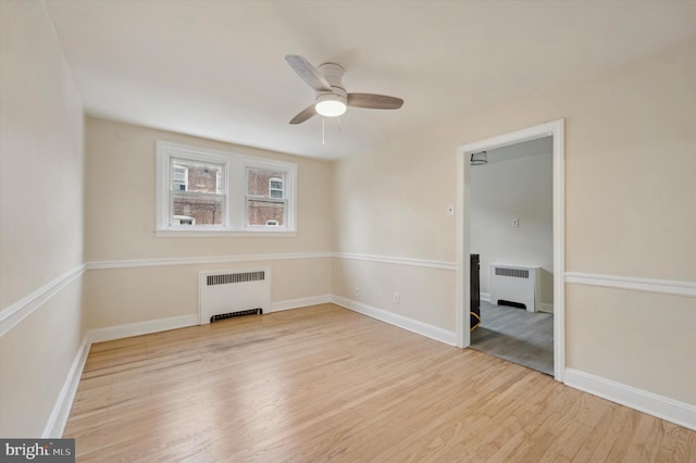 empty room featuring ceiling fan, radiator heating unit, and light hardwood / wood-style flooring