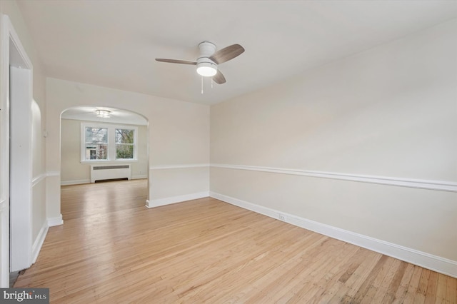 unfurnished room featuring ceiling fan, radiator, and light hardwood / wood-style flooring