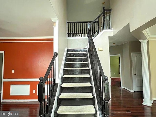 stairway with hardwood / wood-style floors, ornamental molding, and ornate columns