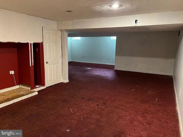 unfurnished room with a textured ceiling and dark colored carpet