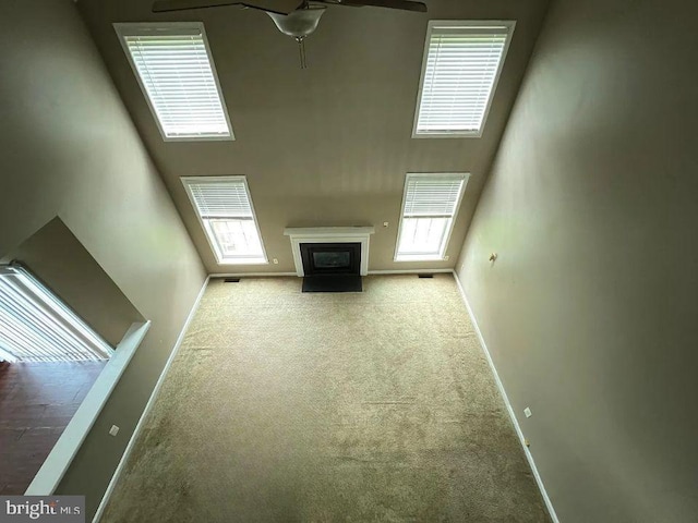 unfurnished living room with light carpet, ceiling fan, and a healthy amount of sunlight