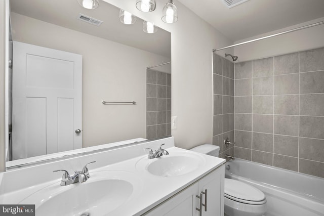 full bathroom with vanity, tiled shower / bath combo, and toilet