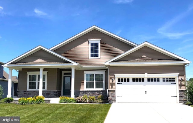 craftsman-style home featuring a front yard, covered porch, and a garage