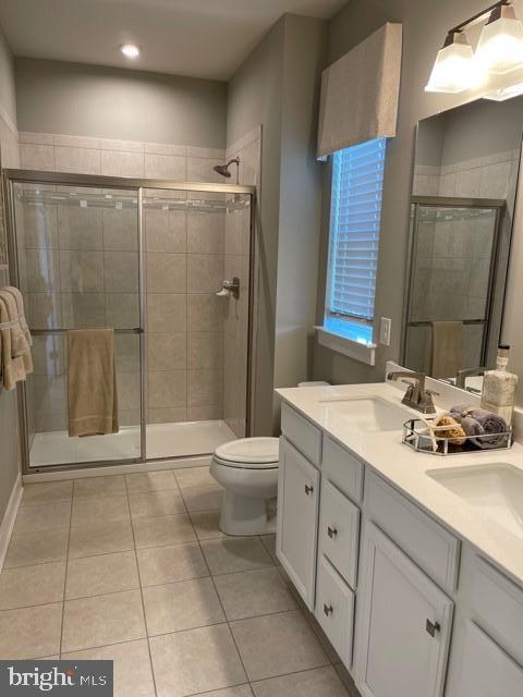 bathroom with a shower with shower door, tile patterned floors, vanity, and toilet