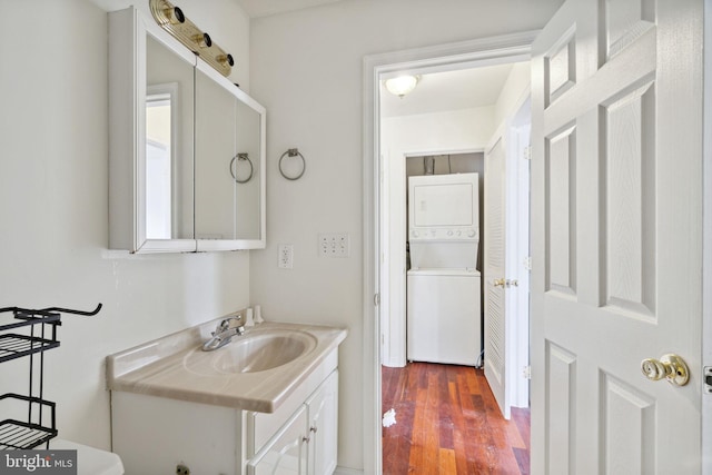 bathroom featuring hardwood / wood-style flooring, stacked washer and dryer, and vanity