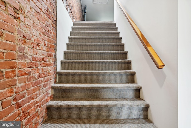 stairway featuring brick wall