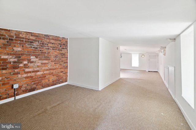 unfurnished room featuring light carpet and brick wall