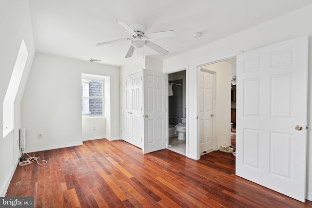 unfurnished bedroom featuring ceiling fan, ensuite bath, and dark wood-type flooring