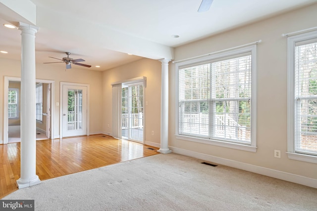 empty room featuring ceiling fan, light carpet, and ornate columns