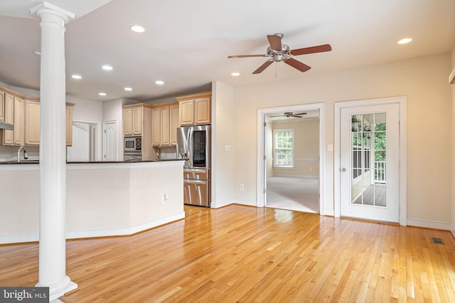 kitchen featuring light wood-type flooring, ornate columns, appliances with stainless steel finishes, and light brown cabinets