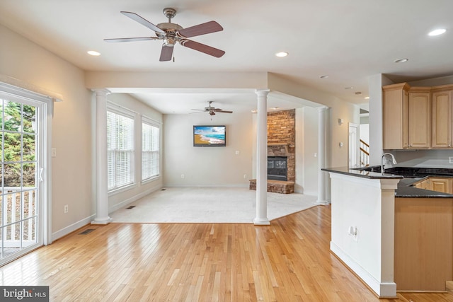 kitchen featuring light hardwood / wood-style floors, kitchen peninsula, decorative columns, light brown cabinetry, and sink