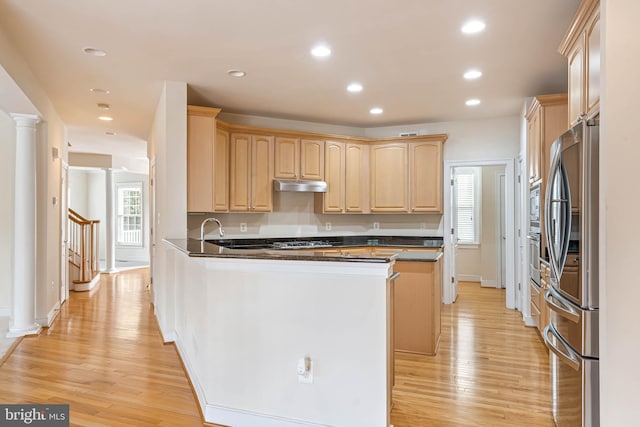 kitchen with light brown cabinetry, a wealth of natural light, stainless steel fridge, and decorative columns