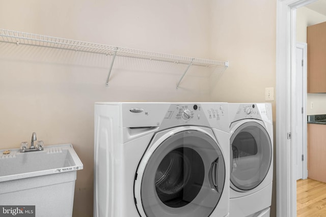 washroom with washer and clothes dryer, wood-type flooring, and sink