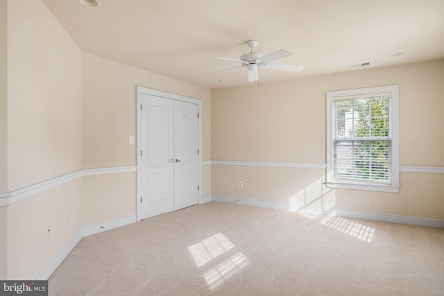 unfurnished bedroom featuring ceiling fan, a closet, and carpet flooring