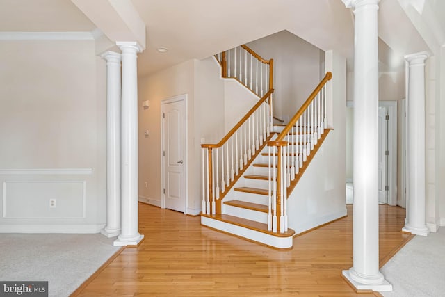 stairway featuring hardwood / wood-style flooring and ornate columns